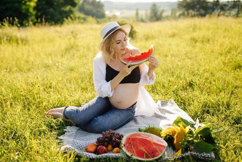 ผู้หญิงท้องกำลังนั่งทานแตงโม
