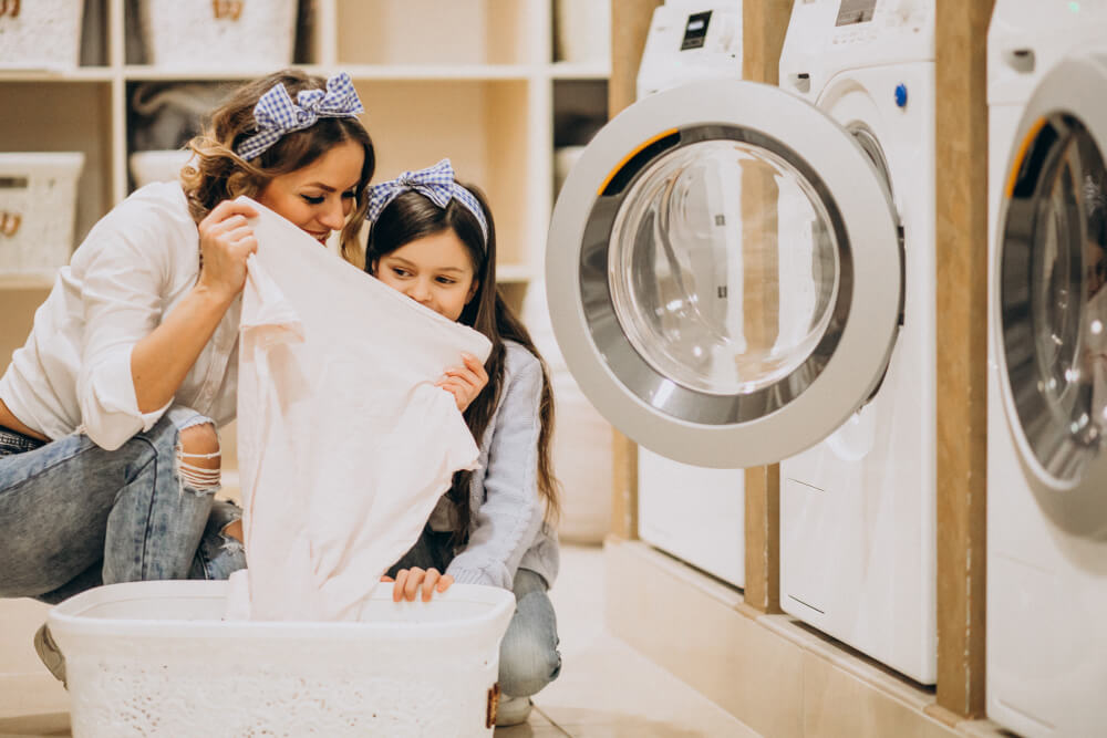 ผู้หญิงกับเด็กกำลังดูเสื้อสีขาวในร้านซักรีด
