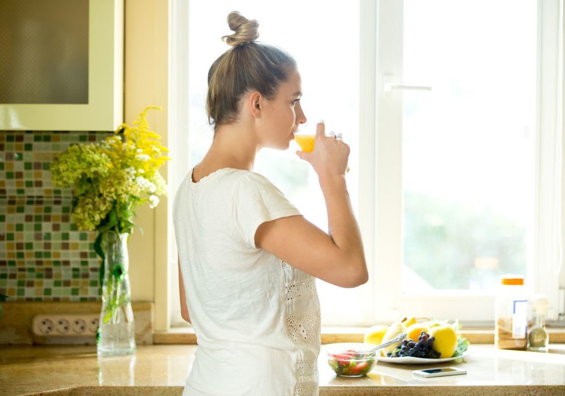 portrait-attractive-woman-drinking-juice-kitchen