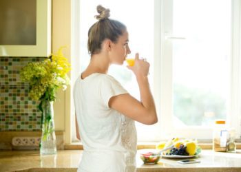 portrait-attractive-woman-drinking-juice-kitchen