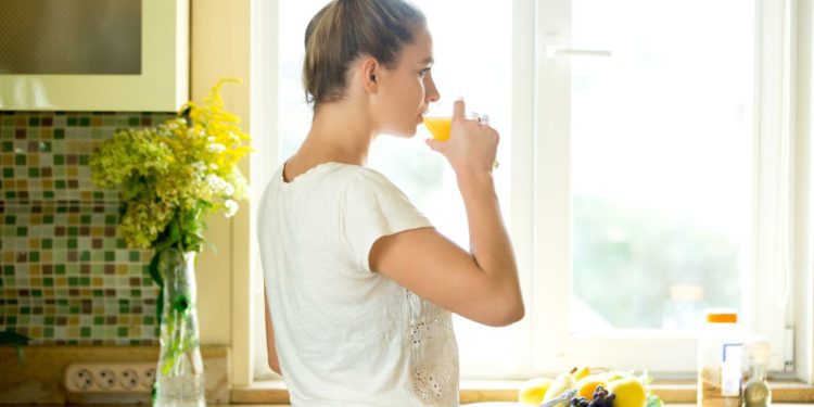 portrait-attractive-woman-drinking-juice-kitchen